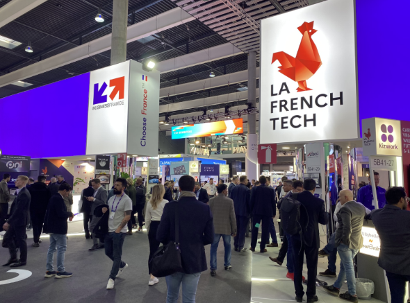 Vue du dynamique Pavillon French Tech lors d'une exposition technologique, avec des visiteurs interagissant et explorant divers stands. nPerf sera présent au MWC 2025 dans cet espace vibrant.